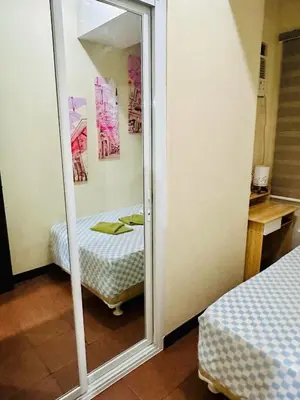 a mirror in a room with a reflection of a bed at Phebestaycation in Manila