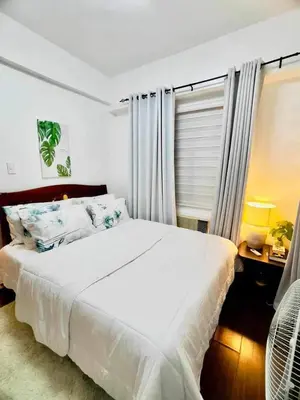 a bedroom with a large white bed and a window at Casa Broganza in Manila
