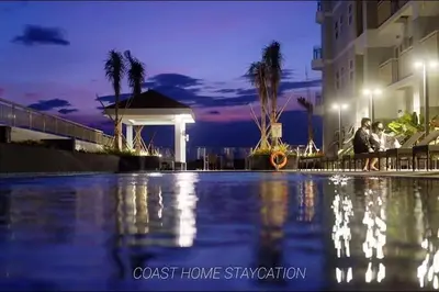 a couple sitting next to a swimming pool at night at Coast Residences Pasay City 1 bedroom in Manila