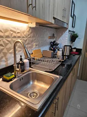 a kitchen sink with a dish rack next to it at Adventura Staycation in Manila