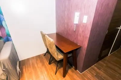 a wooden table with two chairs and a phone on a wall at Air residence Snuggle in Style 1 BR condo Makati swim gym park surf 300 Mb in Manila