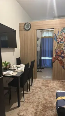 a dining room with a table and chairs and a clock at Jaja staycation in Manila