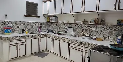 a kitchen with white cabinets and black and white tiles at Short Stay BF Resort in Manila