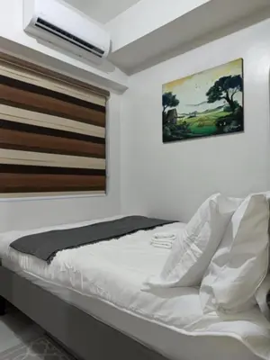a bedroom with a white bed with a painting on the wall at SMDC Red residences Condominium Makati City in Manila