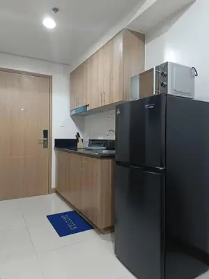 a kitchen with a black refrigerator and wooden cabinets at SMDC Red residences Condominium Makati City in Manila