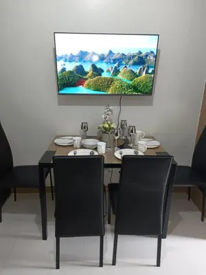 a dining room table with black chairs and a tv on the wall at SMDC Red residences Condominium Makati City in Manila
