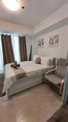 a bedroom with a large bed and a chair at Casa Elisha Azure Urban Resort Staycation in Manila