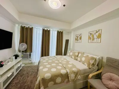 a bedroom with a bed and a couch and a television at Casa Elisha Azure Urban Resort Staycation in Manila