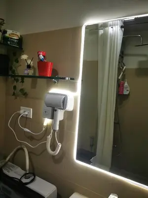 a bathroom with a mirror and a toilet with a light at Aldo mall of Asia shore 3 residence in Manila