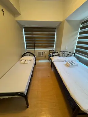 two twin beds in a room with a window at Greenhills commercial center 1-2BR condominium in Manila