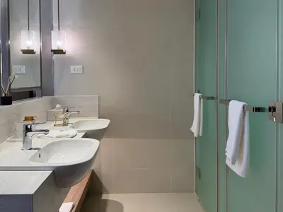 a bathroom with two sinks and a shower at Novotel Suites Celestia at Hotel Residences Manila in Manila