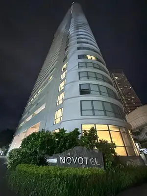 a tall white building with a sign in front of it at Novotel Suites Celestia at Hotel Residences Manila in Manila