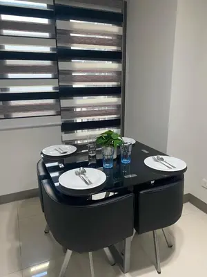 a dining room table with black chairs and plates and glasses at The Skycabin at S Residences in Manila