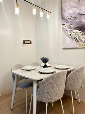 a dining room with a white table and chairs at NEW! The Hive Residences - 1BR with Balcony & FREE Parking at Casa Arbo in Taytay