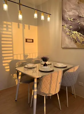 a dining room with a table with chairs and a painting at NEW! The Hive Residences - 1BR with Balcony & FREE Parking at Casa Arbo in Taytay