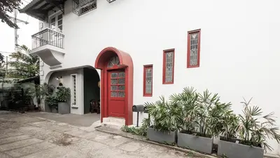 a red door on a white building with plants at MiraNamin Nest BANABA - Garden View Suite in Historic Home - Bathtub, Luxury Indoor Plunge Pool, Guest Kitchen, Self-Service Breakfast, Rooftop, Pet-Friendly in Manila