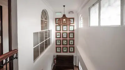 a hallway with a staircase with pictures on the wall at MiraNamin Nest BANABA - Garden View Suite in Historic Home - Bathtub, Luxury Indoor Plunge Pool, Guest Kitchen, Self-Service Breakfast, Rooftop, Pet-Friendly in Manila