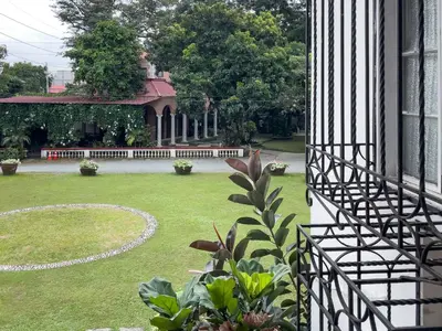 a view of a yard of a house with a garden at MiraNamin Nest CALACHUCHI - Cozy Room in Historic Home - Indoor Plunge Pool, Petite Desk, Garden View with Balcony, Self-Service Breakfast, Guest Kitchen, Rooftop, Pet-Friendly in Manila