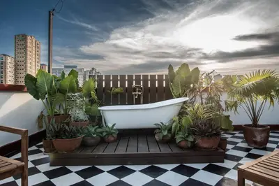 a bath tub sitting on a deck with plants at MiraNamin Nest CALACHUCHI - Cozy Room in Historic Home - Indoor Plunge Pool, Petite Desk, Garden View with Balcony, Self-Service Breakfast, Guest Kitchen, Rooftop, Pet-Friendly in Manila