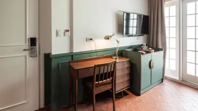 a room with a desk with a lamp and a television at MiraNamin Nest CALACHUCHI - Cozy Room in Historic Home - Indoor Plunge Pool, Petite Desk, Garden View with Balcony, Self-Service Breakfast, Guest Kitchen, Rooftop, Pet-Friendly in Manila