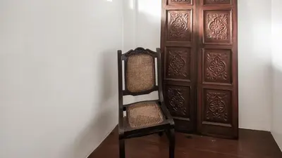a chair sitting in front of a wooden door at MiraNamin Nest KAMANTIGI - Two Bed Suite in Historic Home with Luxury Indoor Plunge Pool, Garden Access, Self-Service Breakfast, Guest Kitchen, Pet-Friendly in Manila