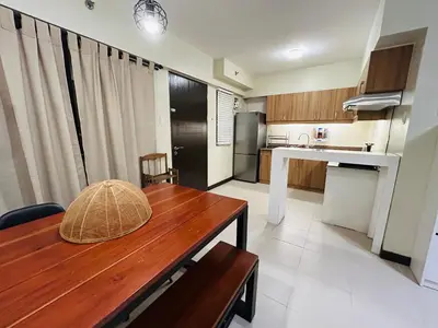 a kitchen with a wooden table in a room at The Mindful Home - 2BR Cozy Condo near NAIA in Manila