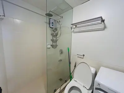 a bathroom with a toilet and a glass shower at The Mindful Home - 2BR Cozy Condo near NAIA in Manila