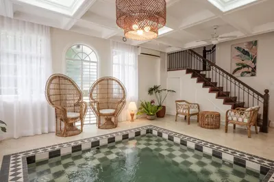 an indoor pool in a house with chairs and a staircase at MiraNamin Nest LIRYO - Family Suite in Unique Historic Home with Indoor Plunge Pool, Garden Access, Self-Service Breakfast, Guest Kitchen in Manila