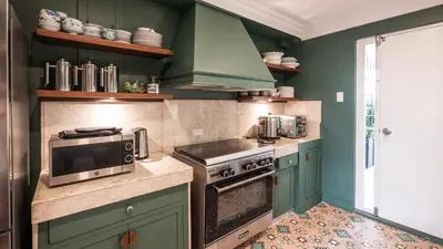a kitchen with green cabinets and a stove and microwave at MiraNamin Nest LIRYO - Family Suite in Unique Historic Home with Indoor Plunge Pool, Garden Access, Self-Service Breakfast, Guest Kitchen in Manila