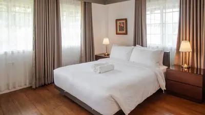 a large white bed in a room with windows at MiraNamin Nest ROSAL - Garden View Suite in Unique Historic Estate with Indoor Plunge Pool, Self-Service Breakfast, Guest Kitchen in Manila
