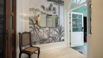 a hallway with a chair and a wallpaper with palm trees at MiraNamin M A P I L I G - Private Suite in Historic Home with Unique View, Self-Service Breakfast, Indoor Plunge Pool, Rooftop, Shared Kitchen in Manila