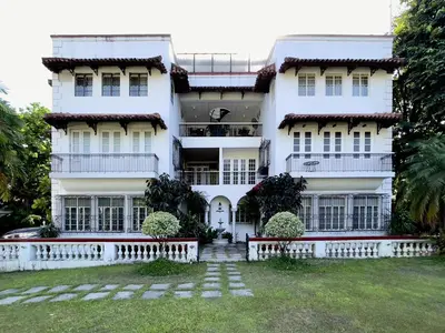 a white building with a yard in front of it at MiraNamin M A P I L I G - Private Suite in Historic Home with Unique View, Self-Service Breakfast, Indoor Plunge Pool, Rooftop, Shared Kitchen in Manila