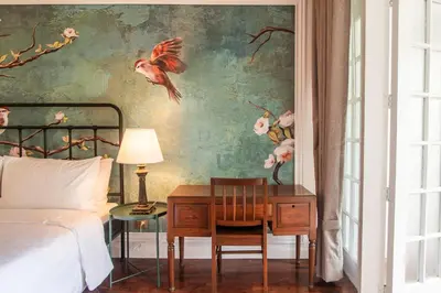 a bedroom with a bed and a desk with a bedside table at MiraNamin SAMPAGUITA - Two Bedroom Suite in Historic Home with Indoor Plunge Pool, Self-Service Breakfast, Garden View, Pet-Friendly in Manila