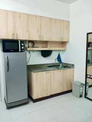a kitchen with wooden cabinets and a stainless steel refrigerator at SM MEZZA 1 RESIDENCES Studio Room Gian Thyresse Crib in Manila