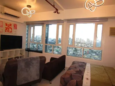 a living room with a couch and a tv and windows at SM MEZZA 1 RESIDENCES Studio Room Gian Thyresse Crib in Manila