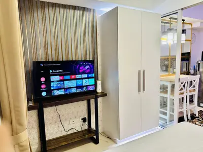 a television on a stand in a room with a door at We Vibe, Azure Urban Resort Residences in Manila