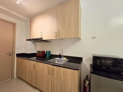 a kitchen with wooden cabinets and a sink and a microwave at 1BR Condotel with Balcony at SM Light Residences #LT12 in Manila