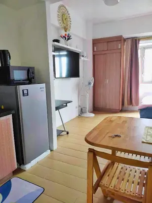a living room with a table and a refrigerator at Jennie's Lucky 5M Suite in Manila