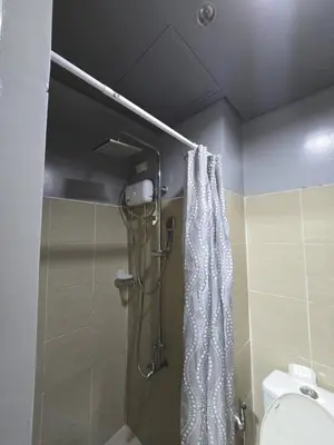 a shower in a bathroom with a white shower curtain at Shore Residences Cozy oasis by Richnells Tower D in Manila