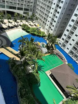 an overhead view of a pool with palm trees and a tennis court at Shore Residences, Vintage charm by Richnells Tower D in Manila