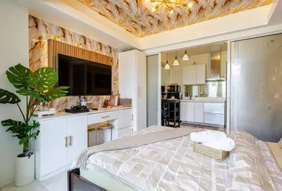 a bedroom with a large bed with a tv on the wall at Miami suites in Manila