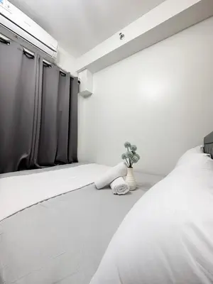 a bedroom with a white bed with a potted plant at 1573 Budget Condo near MOA and Airport in Manila