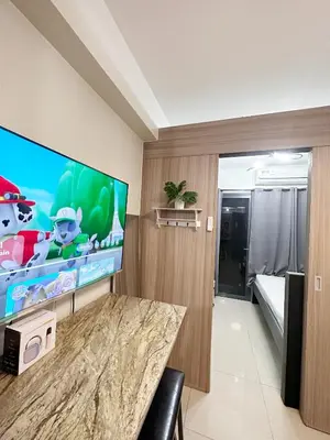 a room with a large screen tv and a bedroom at 1573 Budget Condo near MOA and Airport in Manila