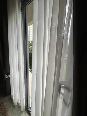 a window with white curtains in a room at Chelsea Tower 3 in Manila