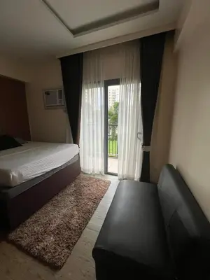 a bedroom with a bed and a couch and a window at Chelsea Tower 3 in Manila