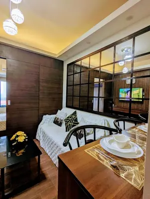 a living room with a bed and a table with a dining room at 1 bedroom Cozy Escape in Manila