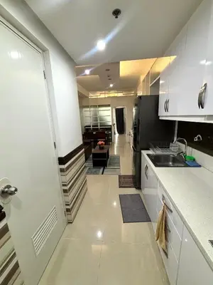 a kitchen with white cabinets and a sink and a staircase at White House Staycation by Trixie Datiles in Manila