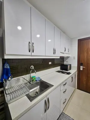 a kitchen with white cabinets and a sink at White House Staycation by Trixie Datiles in Manila
