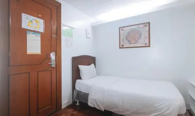 a small room with a bed and a door at Comfy Inn Manila Kalaw by RedDoorz in Manila