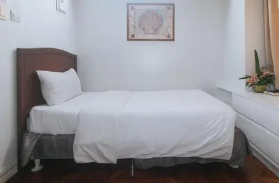 a bedroom with a bed with white sheets and a picture at Comfy Inn Manila Kalaw by RedDoorz in Manila